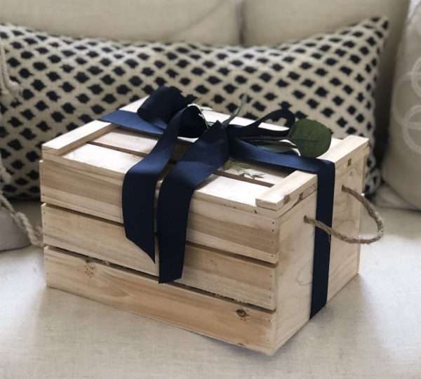 Brown baby crate placed on a couch with blue bow