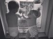 two babies in diapers waiting at door