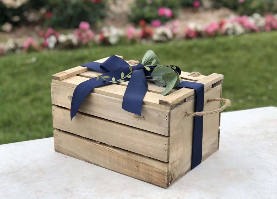wooden crate tied in blue ribbon and a spring of green used to pack with baby items for a beautiful presentation of a baby gift