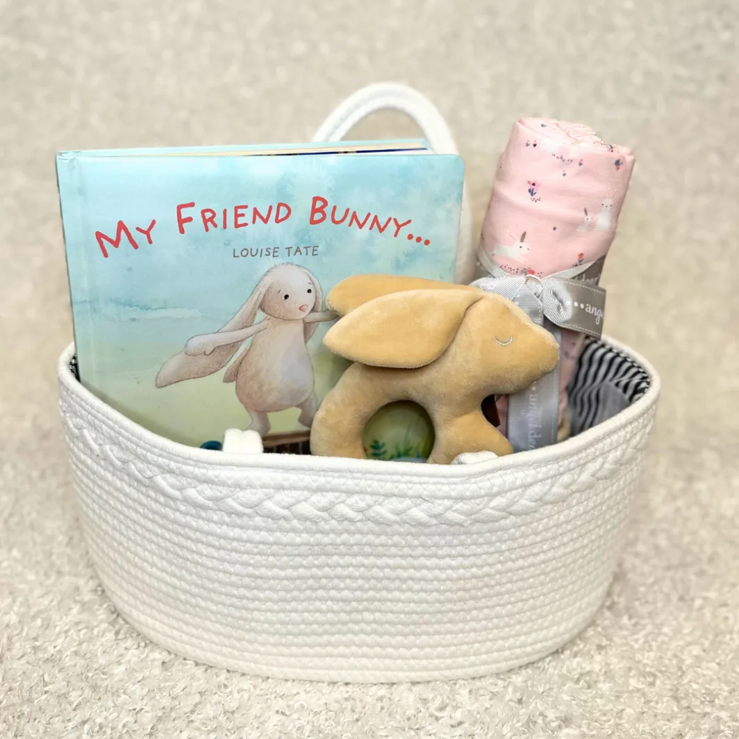white basket with the popular children's book My Friend Bunny, a soft pink bunny baby blanket and a soft plush bunny shaped rattle