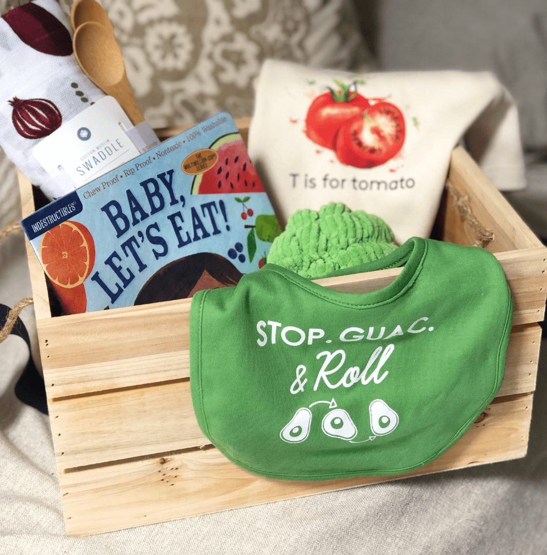 wooden box baby gift with market print swaddle, tomato print onesie, bay let's eat book for baby and a big and brocolli rattle