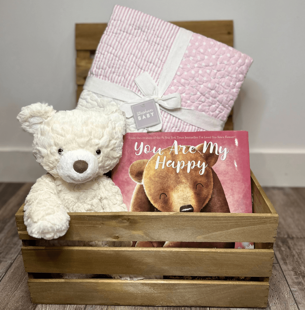 wooden box with a baby quilt, teddy bear, and book for elegant baby shower gift