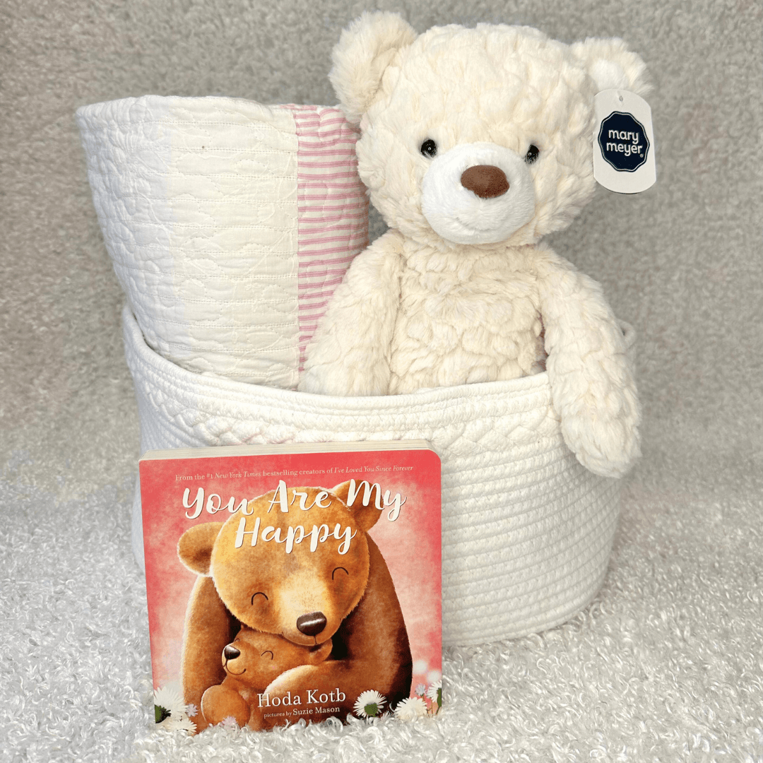 Pink Quilt Basket - Baby Showers By Mail white basket with a baby quilt, teddy bear, and book for elegant baby shower gift